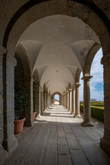 arched walkway with granite floors and gardens with hedges on the open side