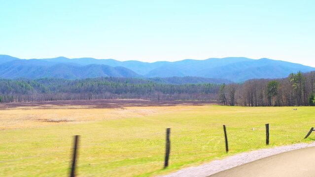 Pov point of view car vehicle side shot driving on Cades Cove scenic loop road drive by green pasture field at Great Smoky Mountains National Park, Gatlinburg Tennessee in spring