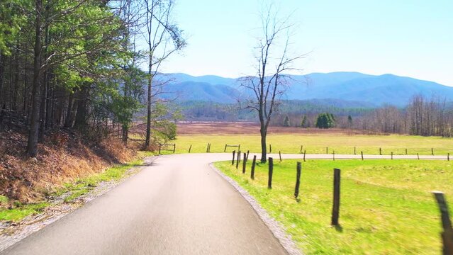 Pov point of view car vehicle shot driving on Cades Cove scenic loop road drive by green pasture field at Great Smoky Mountains National Park, Gatlinburg Tennessee in spring