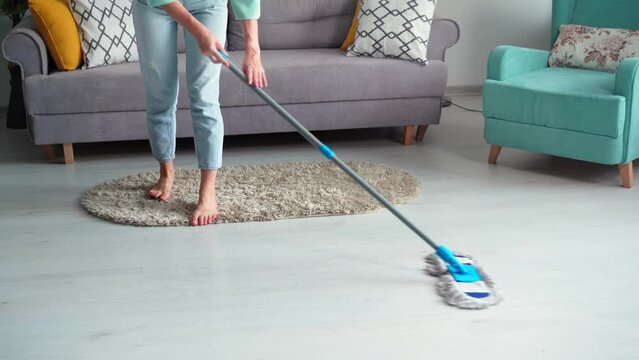 cleaning, a young woman with a mop in her hands washes the floor in the room from dust and dirt