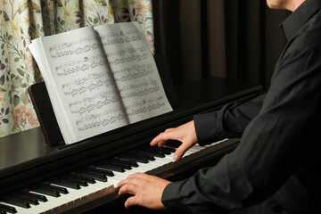 black piano and sheet music, man plays