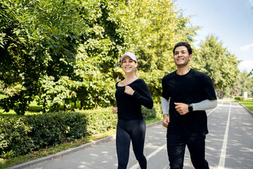 Running down the street, man and woman fitness training fast running. They use a fitness watch on their arm.