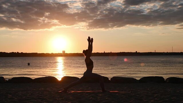 Slow motion video of a young woman doing yoga workout on Baltic sea coastline during subset