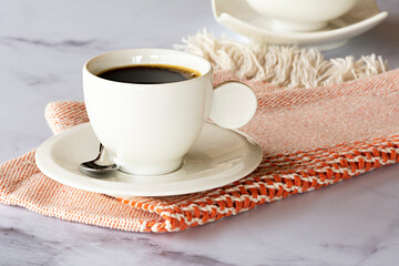 Cup of coffee from Brazil for logo application. White cup for mockup on a marble stone with straw and orange tablecloth handcrafted in Tear Mineiro