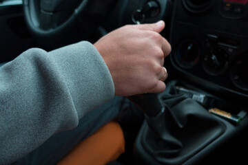 Man hand holding the gear lever of a car, transmission. Grey fleece sweater. Change. Sitting....