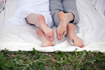 Couple in love in the city park on vacation. The lovers' bare feet touch each other. Selective focus.