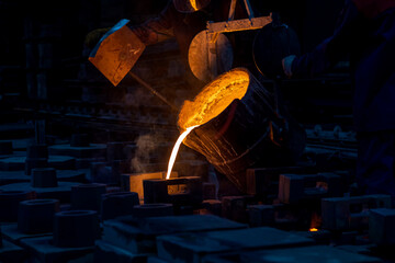 Liquid metal or cast iron poured into molds. Metal casting process with red high temperature fire...