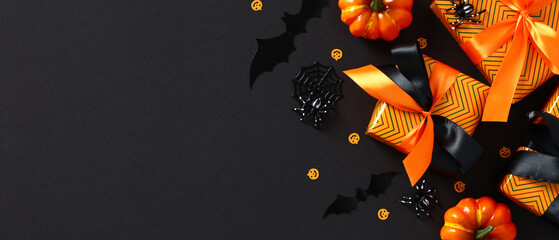 Happy Halloween sale banner design. Top view orange gift boxes with ribbon bow, bats, spiders, glitter confetti on black background.