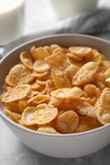 Tasty cornflakes with milk in bowl on table, closeup