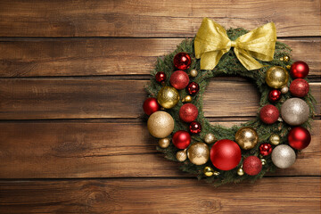 Beautiful Christmas wreath with festive decor on wooden background. Space for text