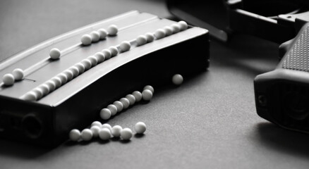 White plastic bullet balls of airsoft gun or bb gun on dark floor, soft and selective focus on white pellets. - obrazy, fototapety, plakaty