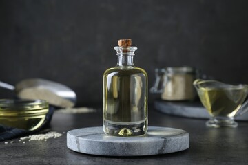 Obraz na płótnie Canvas Sesame oil in glass bottle on dark grey table