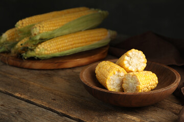 Tasty sweet corn cobs on wooden table. Space for text