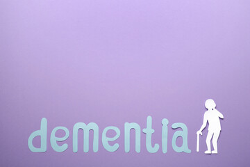 Word Dementia and old person paper cutout on violet background, flat lay. Space for text