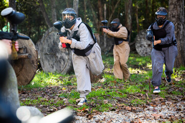 Fototapeta premium Group of people in full gear playing paintball on shooting range