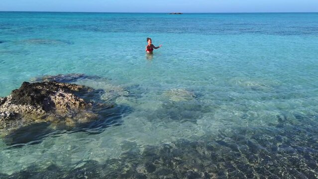 Young enthusiastic girl takes advantage of being alone in the turquoise waters of Elafonisi beach to dance