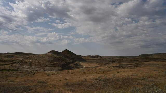 Time lapse of clouds moving over a badlands desert setting in fall brown colors.
