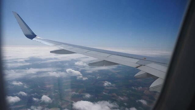 View from passenger window of wing of airplane flying in sky on sunny day. Concept of successful travel