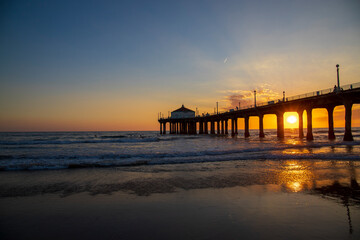 a gorgeous summer landscape at the Manhattan Beach Pier with a stunning sunset in the sky with blue...