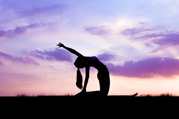 The slender girl is doing a yoga warm-up exercise outdoors