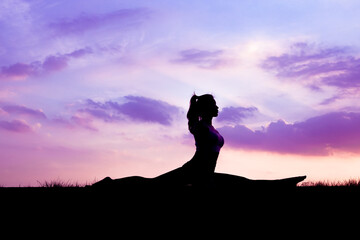 The slender girl is doing a yoga warm-up exercise outdoors