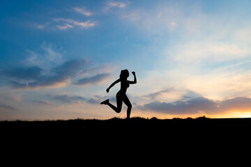 The silhouette of the back of a girl jumping and running in the morning glow