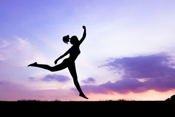 The silhouette of the back of a girl jumping and running in the morning glow