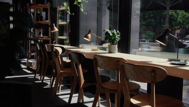 Minimalistic Caf&eacute; interior on a sunny day. Plant, Table, chairs in front of glass front. 4K Close Up.