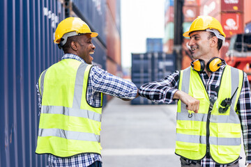 Caucasian businessman elbow bump with African worker in container port