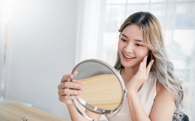 Closeup portrait of young beautiful asian girl with mirror makeup routine with copy space. Beauty...