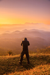 silhouette of a photographer shoots a sunrise in the high mountains. Sunrise, sunset and landscape sky in outdoor beautiful.