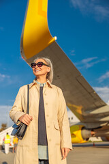 Cheerful female traveler standing outdoors at airport