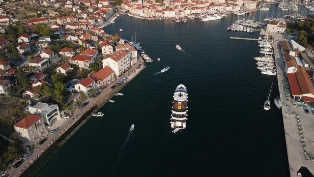 Drone follow shot of cruise ship coming back to port of Mila, Brac Island, Croatia. Warm colors of golden hour at sunset over the waters of Adriatic Sea.