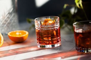 Photo composition of two Negroni glass cocktail with sun light and shadow and orange