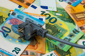 Grey electric plug on euro banknotes