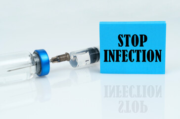 On a white reflective surface there is a syringe with an ampoule and a plate with the inscription - STOP INFECTION