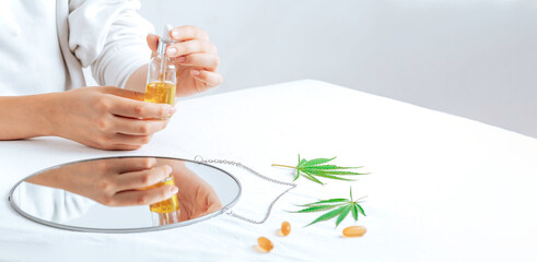 Banner with cbd oil in hands. Pharmaceutical medicine pills, capsules on a white table. Concept...