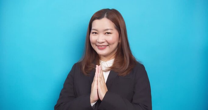 Beautiful Thai businesswoman in a black suit guests Sawadee with a smile on blue background