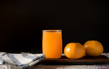 glass of fresh orange juice with fresh fruits on dark background, high Vitamin C, orange drink