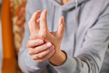 Senior woman suffering from hand and finger joint pain, inflammation