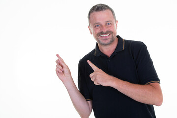 Portrait of handsome happy casual older man smiling showing pointing at invisible product or text at white wall isolated on white background copy space