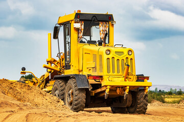 Road grader at the construction site. Powerful construction machine for ground leveling and excavation. Close-up. Professional construction equipment.