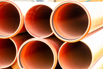 Orange sewer pipes at the construction site. Preparation for the installation of an underground sewer system. Wastewater disposal.