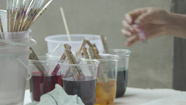 People's hands are mixing paints in a container to use in making beautiful paintings.