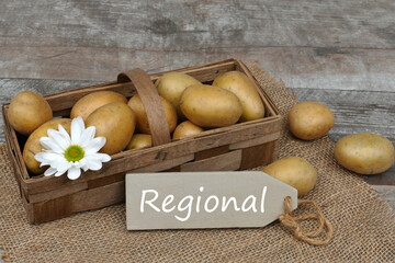 Kartoffeln aus der Region mit dem Wort regional auf einem Holzschild.