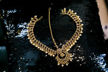 Indian bride's wedding jewellery with pearls on black shiny surface close up