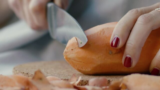 Detail of a hand cutting a whole sweet potato and turning it into pieces, in slow motion