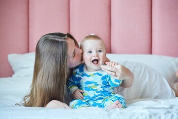 Mom with her newborn baby boy in the bedroom on the bed. The concept of motherhood and childhood.