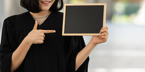 Young smiling woman holding and pointing at black bank blackboard.