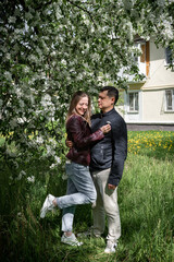 Portrait of a young couple in love man and woman in a spring blooming park hugging and laughing, family good relationship concept